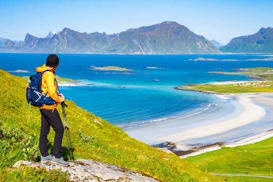Female hiker enjoys spectacular view over mountains and Yttersand beach from trail to Roren, Lofoten Islands, Norway