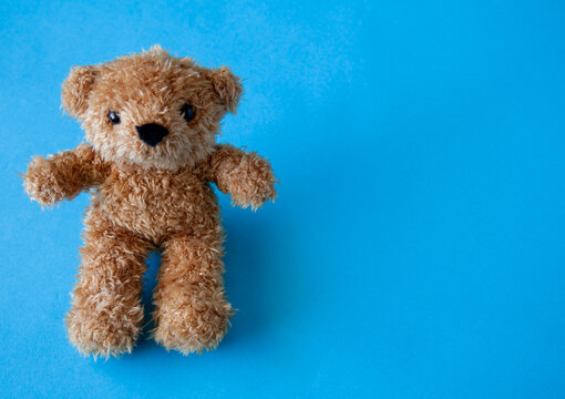 An adorable brown teddy bear sitting against a vibrant blue background with empty space for copy. Perfect for children&rsquo;s themes, baby announcements, gift cards, and playful design projects.

