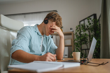 tired man wear headset and work from home on and laptop have headache
