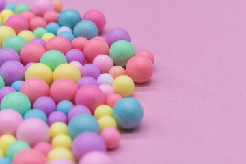 Pastel-colored candy balls in various sizes scattered on a pink background – playful and vibrant flat lay for themes like sweets, childhood, celebration, food styling, and colorful lifestyle