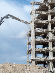 Building demolition progresses at an urban construction site with machinery removing concrete in...