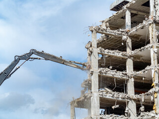 Construction crew demolishes a high-rise building during daytime in an urban setting