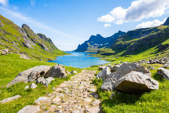 Walking path among green mountain landscape from Bunes beach to Kirkefjord in summer, Lofoten Islands, Norway
