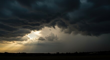 Obraz premium Dark storm clouds fill the sky with light breaking through to the horizon.