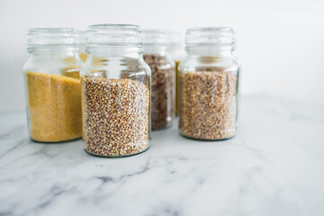clear pantry jars with different types of grains in them including quinoa rice buckwheat couscous and barley, simple ingredients concept