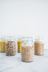 clear pantry jars with different types of grains in them including quinoa rice buckwheat couscous and barley, simple ingredients concept