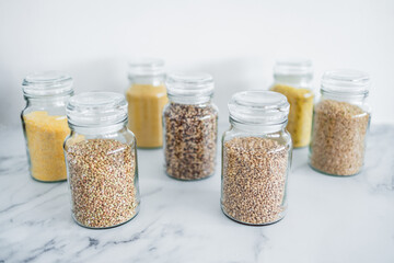 clear pantry jars with different types of grains in them including quinoa rice buckwheat couscous and barley, simple ingredients concept