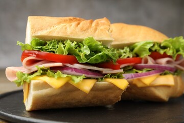 Pieces of tasty baguette sandwich with ham, cheese and vegetables on table against grey background, closeup