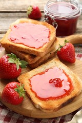Toasts with tasty strawberry jam and fresh berries on table, closeup