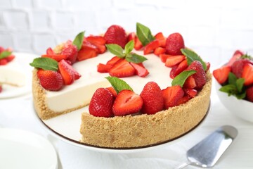 Delicious cheesecake with strawberries and mint on white table, closeup