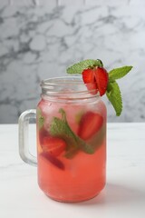 Refreshing drink with strawberries and mint on white table against grey marble background, closeup