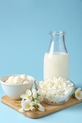 Fresh dairy products and jasmine flowers on light blue background, closeup