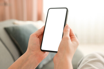 Woman using modern smartphone on sofa at home, closeup