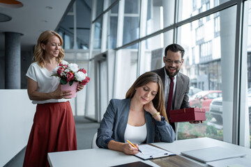 Businesswoman signing contract receiving gifts from colleagues