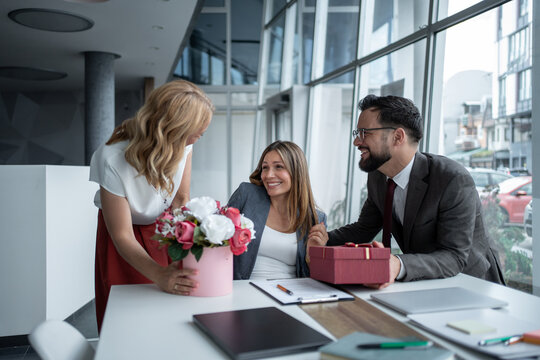 Business people giving gifts and flowers to pregnant colleague in office - Powered by Adobe