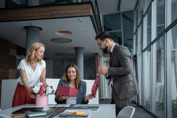 Business team giving gifts and flowers to pregnant colleague in office
