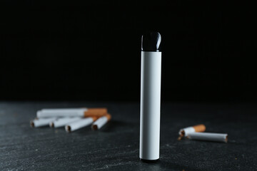 Electronic smoking device and cigarettes on black table