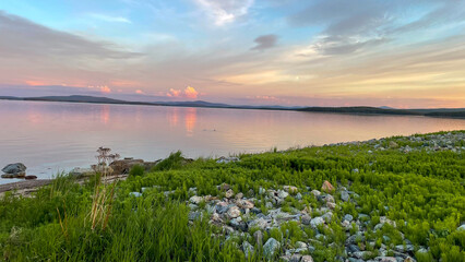  Open lake under evening sky with colorful cloud patterns and soft reflections. A peaceful moment in pristine nature.