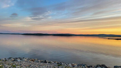  Quiet lakeshore under a pastel sunset sky with calm water and peaceful atmosphere.