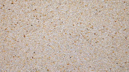 Top view of exposed aggregate surface with gravel stone in off-white cream and ochre tones with light cement or concrete for wall, slab, tile, floor, interior, exterior. Cladding, natural texture. 