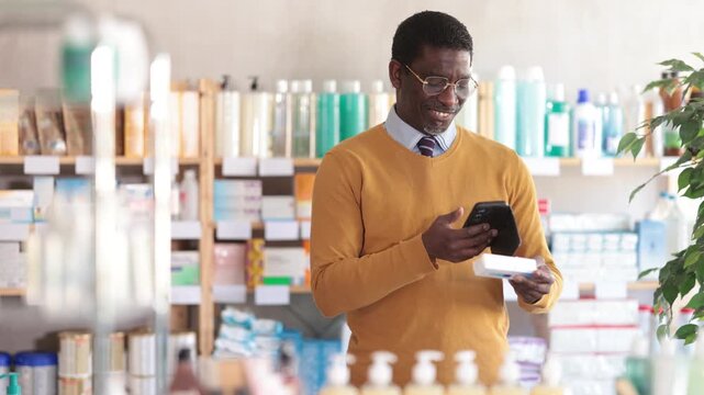  Adult man buyer scanning qr code for box of ointment in pharmacy. High quality 4k footage