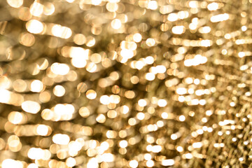 Abstract golden light reflections creating a warm, blurry background of shimmering bokeh circles.