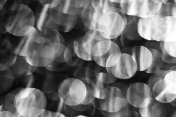 Abstract bokeh background with bright out-of-focus spots in a grayscale presentation.