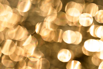 Out-of-focus golden lights create a bokeh effect, forming sparkling circles, abstract background.