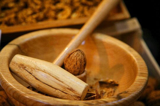 Close-up of a traditional wooden nutcracker and walnut in a carved wooden bowl. The image captures the natural texture and craftsmanship of the nutcracker, creating a warm, rustic culinary atmosphere.