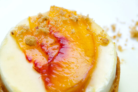 A macro shot of a peach cheesecake topped with fresh peach slices and a delicate crumble, captured with mouthwatering detail. Perfect for showcasing gourmet desserts, baking, and summer treats.