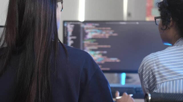 A team of female software developers in a pair programming session, reviewing and debugging code together. Concept for Women in Tech, agile development, and collaboration.