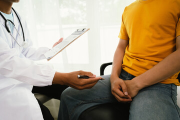 A male patient consults a doctor during a medical exam focused on prostate or testicular health,...