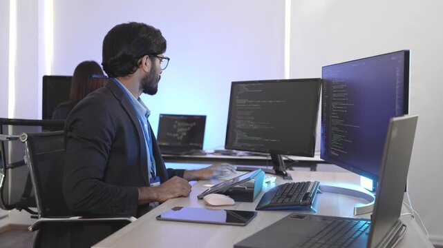 An Indian FinTech engineer engrossed in algorithmic trading platform development at a multi-display rig. Concept for quantitative finance and high-frequency data streams.