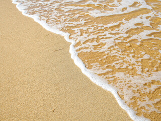 Wave of the sea on a sandy pink beach creating sea foam. Calm ocean water waves splashing sandy beach. Close up sea waves breaking sand beach. Top view, nature background travel relax.