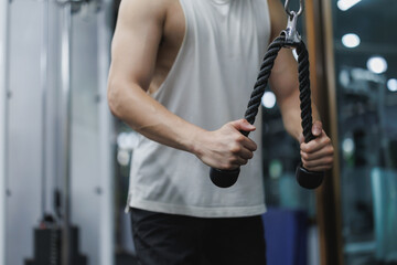 Sportsman exercising triceps with rope cable machine in gym