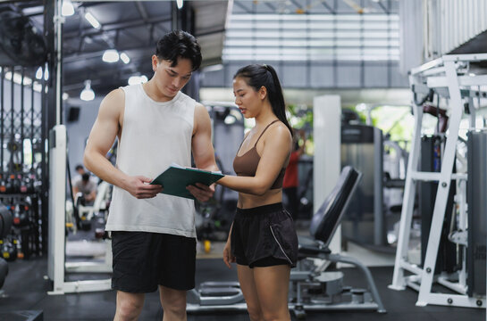 Personal trainer showing workout plan to client in gym