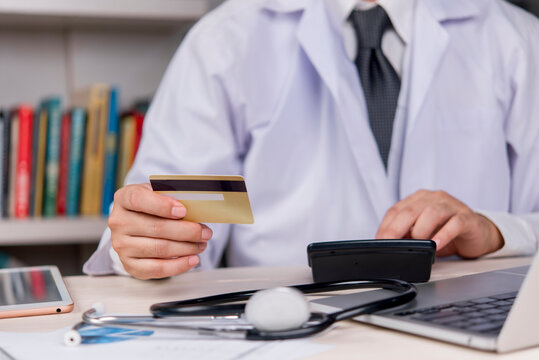 Healthcare and financial concept. Doctor professional receiving payment with a credit card in the hospital. Medical billing, health insurance and hospital administration service.