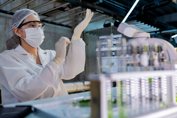 Female scientist in a sterile lab coat and gloves prepares for research in a futuristic...