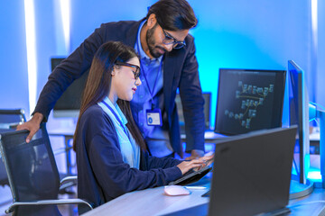 A senior software engineer leads a code review session, mentoring his diverse team on a complex...