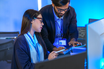 A senior software engineer leads a code review session, mentoring his diverse team on a complex...