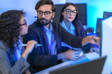 A data science team collaborates, analyzing a neural network model and code on multiple screens. Concept for AI development, machine learning, and data analysis.