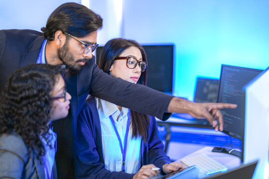 A data science team collaborates, analyzing a neural network model and code on multiple screens. Concept for AI development, machine learning, and data analysis.