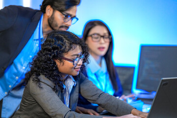 A data science team collaborates, analyzing a neural network model and code on multiple screens. Concept for AI development, machine learning, and data analysis.