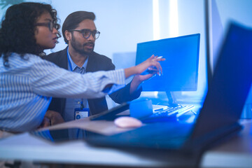 Two diverse software developers celebrate a breakthrough, happily discussing a successful project. Concept for teamwork, innovation, and success in the tech industry.