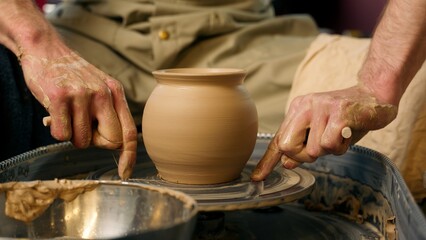 Master hands apron holding thread potter clay craft artisan man craftsman cutting wet vessel pottery wheel completed vase workshop finished pot handmade ceramics male manufacturing work process studio