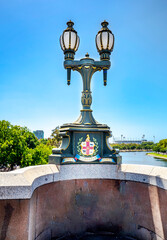Fototapeta premium Cast iron lamp post with Vicorian Coat of Arms in the Princes Bridge, Victorian style, upon the Yarra River, street light in Melbourne, Australia, Dec 2019.