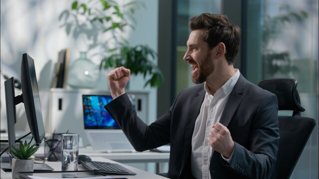 Happy Caucasian adult man working with computer pc reading good news victory winner male winning employee guy business joyful businessman success manager office worker win executive achieve celebrate