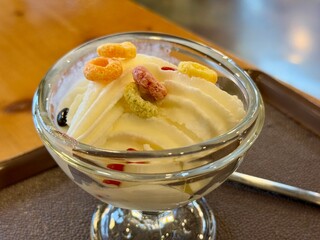 A bowl of yoghurt ice cream on a transparent bowl with colorful cereals on top of it. Served on a table in a cafe