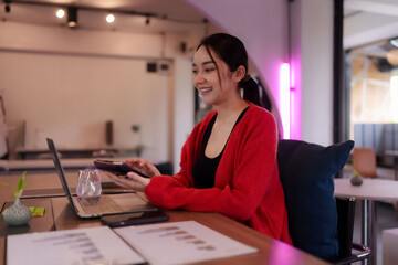 Adult Asian woman freelancer achieving productivity at modern coworking space using laptop for remote business success