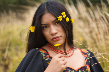 Indigenous model wearing traditional dress and flowers in her hair posing in a field